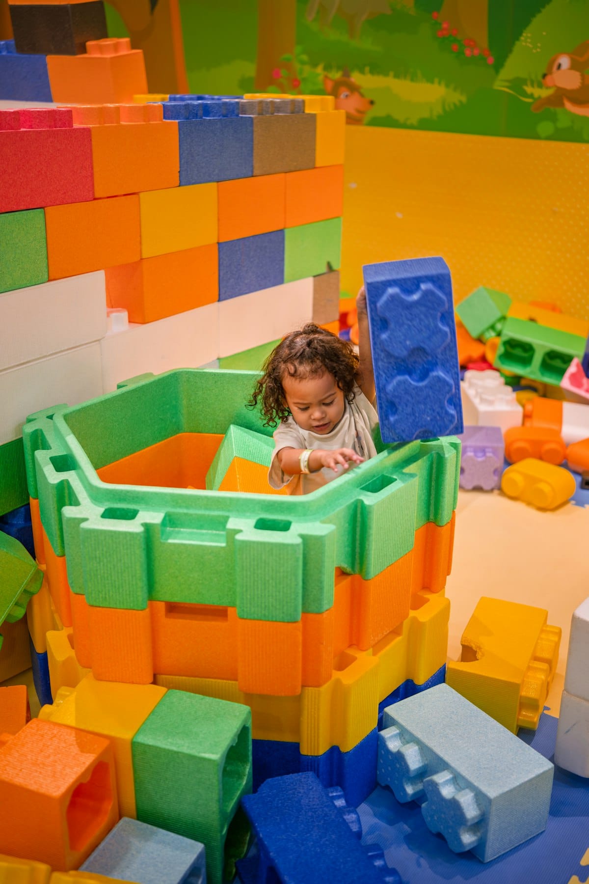 A child building inside a fort of giant foam blocks.
