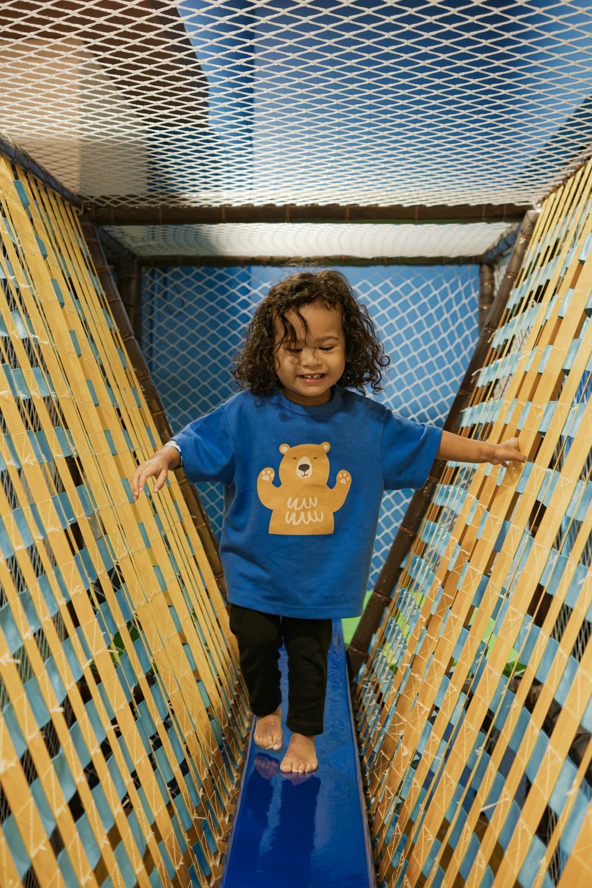A smiling child crossing the rope bridge.