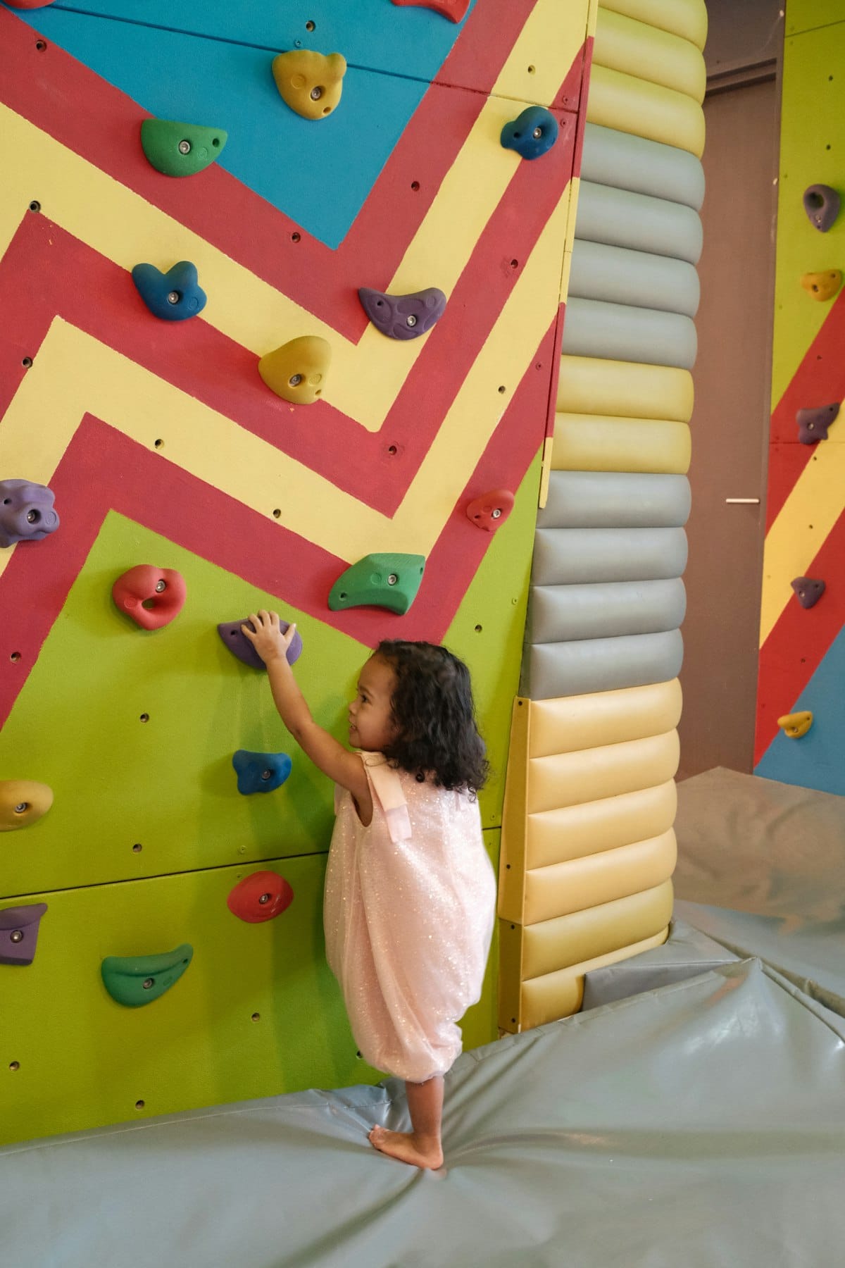 A child climbing the colorful rock wall.